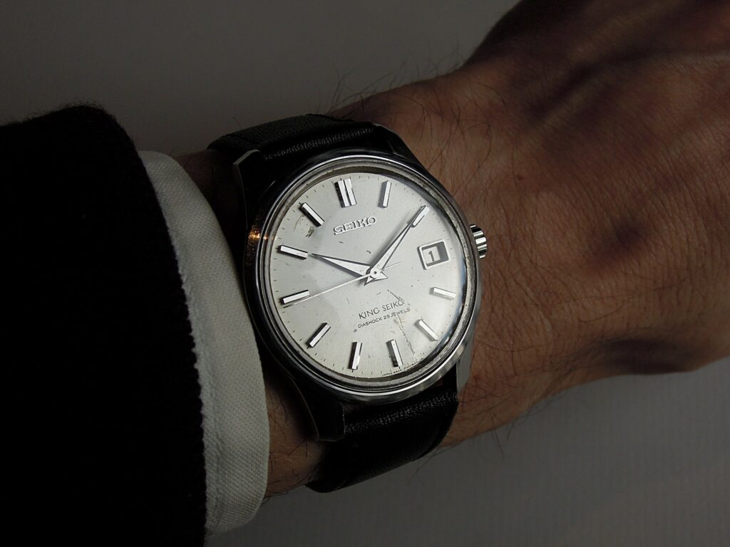 Image of a mens watch on a wrist, the watch is in used condition with scratches and some dents. This is our guide to finding pre-owned watches for sale.