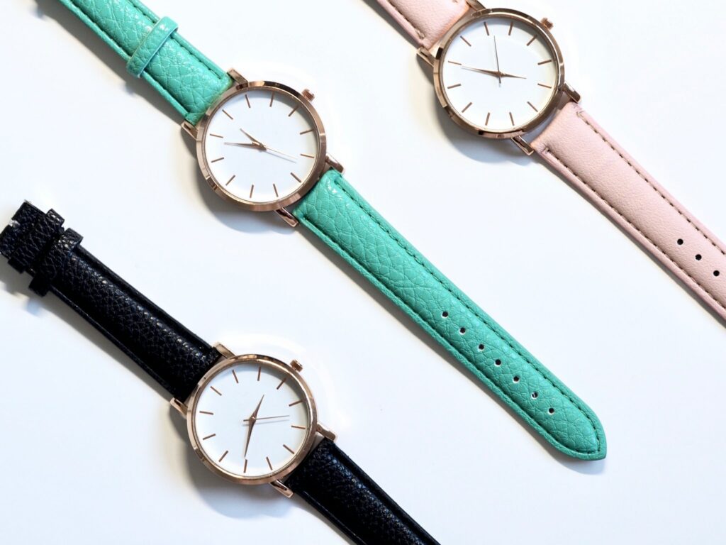 Three watches in a flat-lay, each with a different coloured strap. 