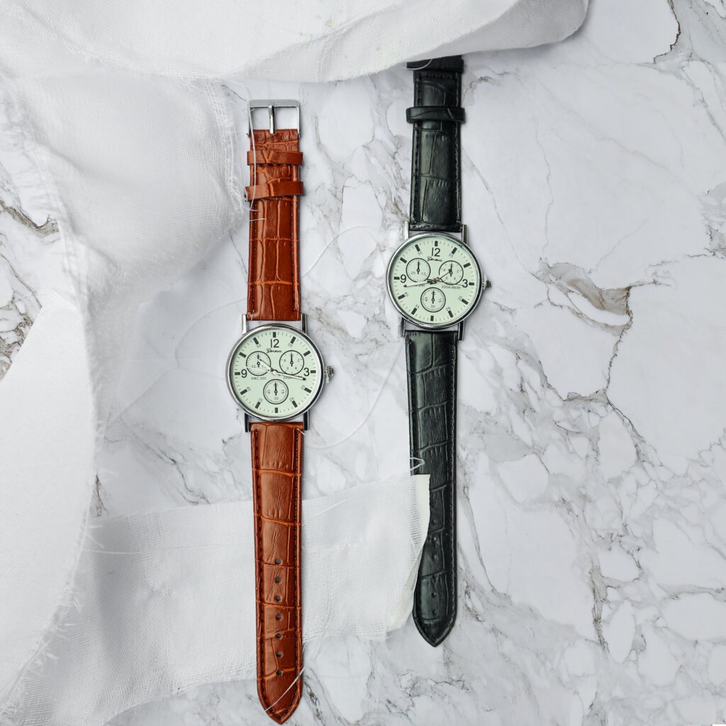 Aerial view of two identical watches with different coloured leather straps - one brown and one black.